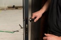 A carpenter installs a metal doorknob for an interior door, Royalty Free Stock Photo
