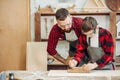 Caucasian male carpenter embracing his son to use plane while working with wood Royalty Free Stock Photo