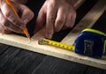 A carpenter makes pencil marks on a block of wood. Hands of the master close-up at work. Working environment in a carpentry Royalty Free Stock Photo