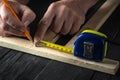 A carpenter makes pencil marks on a block of wood. Hands of the master close-up at work. Working environment in a carpentry Royalty Free Stock Photo