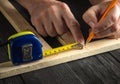 The carpenter makes pencil marks on block of wood. Hands of the master close-up at work. Working environment in carpentry workshop Royalty Free Stock Photo