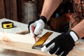 Carpenter man notes with a pencil on the board marks for cutting, male hands with a pencil closeup on a wooden board. Woodwork Royalty Free Stock Photo