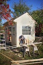 Carpenter Man Using Circular Saw Building a Small Garden Cottage Shed Royalty Free Stock Photo