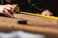 Carpenter man using measuring tape looking wood size at workspace. craftsman profession in wood factory