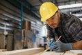 Carpenter man wear gloves during working using tape measure and pencil to make marks piece of wood Royalty Free Stock Photo