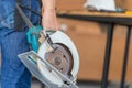 Carpenter man working in wood workshop. Handyman manual worker in tools belt and holding circular saw in his hands Royalty Free Stock Photo