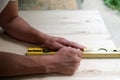 Carpenter marking straight line on plywood sheet using spirit level in carpentry workshop. Measuring, drawing line, DIY concept Royalty Free Stock Photo