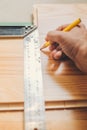 carpenter marks the smooth cutting line on the board with the help of a construction square and a pencil