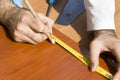 Carpenter measures the distance using a measure and marks with a carpenter`s pencil.