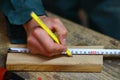 The carpenter measures the length of the wooden part and works
