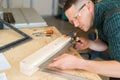 Carpenter measures wooden planks in the workshop.