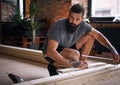 Carpenter measuring boards in a room with loft interior.