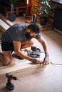 Carpenter measuring boards in a room with loft interior.