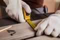 Carpenter is measuring length of wood planks or timbers by measuring tape or ruler. Carpenter workspace, craftsman entrepreneur Royalty Free Stock Photo