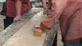 Carpenter in Medieval Cotton Clothes Working With a Wood by Plane. Man Manually Hews a Wooden Board With a Plane