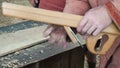 Carpenter in Medieval Cotton Clothes Working With a Wood by Plane. Man Manually Hews a Wooden Board With a Plane