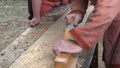 Carpenter in Medieval Cotton Clothes Working With a Wood by Plane. Man Manually Hews a Wooden Board With a Plane