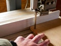 Carpenter with a missing finger cutting a piece of plywood at the bandsaw