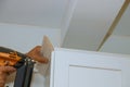 Carpenter nailing crown moldings in the kitchen cabinets framing trim worker using brad nail gun