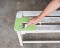 Carpenter painting green color to white wooden bench