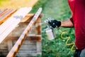 carpenter painting timber with spraygun, outdoors Royalty Free Stock Photo