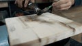 A carpenter paints a piece of wood for a loft-style chair with a brush. Close up