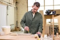 Carpenter paints wooden slat for production of furniture on table in workshop