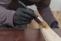 Carpenter paints wooden slat for production of wooden garden bench on table in carpentry workshop