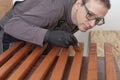 Carpenter paints wooden slat for production of wooden garden bench on table in carpentry workshop