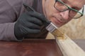 Carpenter paints wooden slat for production of wooden garden bench on table in carpentry workshop