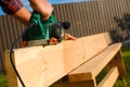 A carpenter planes a wooden board with an electric plane. Planing wooden plank with a electric plane. Close-up on hands with an Royalty Free Stock Photo