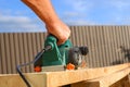 A carpenter planes a wooden board with an electric plane. Planing wooden plank with a electric plane. Close-up on hands with an Royalty Free Stock Photo