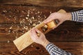 Carpenter planes a workpiece on a workbench. carpenter`s hands. old wooden plane Royalty Free Stock Photo