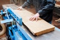 Carpenter plans a board in a carpentry workshop on a large stationary machine