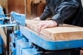 Carpenter plans a board in a carpentry workshop on a large stationary machine close-up. soft focus