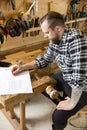 Carpenter plans projects and takes notes on drawing in workshop Royalty Free Stock Photo