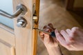 Carpenter repairing door lock. Installing a door handle. Handyman tightening door hinge . Hands of the repairman with a Royalty Free Stock Photo