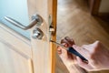 Carpenter repairing door lock. Installing a door handle. Handyman tightening door hinge . Hands of the repairman with a