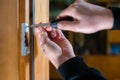 Carpenter repairing door lock. Installing a door handle. Handyman tightening door hinge . Hands of the repairman with a Royalty Free Stock Photo