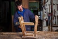 Carpenter restoring Wooden Stool Furniture in his workshop. Royalty Free Stock Photo