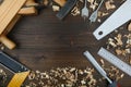 Carpentry tools: planer, chisel, wood saw, square carpenter, ruler, wood drills with wood shavings on a wooden surface top view Royalty Free Stock Photo