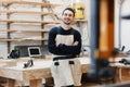 Carpenter`s portrait in work clothes in front of workbench. Portrait of smiling man at work in carpenter workshop. startup