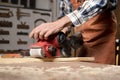 Carpenter sanding wood with belt sander at workshop in wooden board project or woodworking carpentry