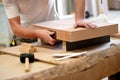 Carpenter sanding a wooden block manually