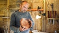 Carpenter in sawdust inspects finished product