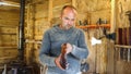 Carpenter in sawdust inspects finished product