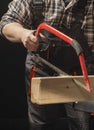 Carpenter sawing a board with a hand wood saw