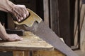 Carpenter sawing a board with a hand wood saw