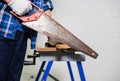 Carpenter sawing a board with a hand wood saw, man working cutting plank with handsaw Royalty Free Stock Photo