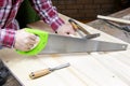 A carpenter is sawing boards. A worker is sawing a plank with a hand saw. Sawing by the hand saw Royalty Free Stock Photo